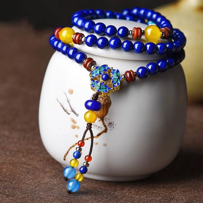 Tibetan Lapis Lazuli Yellow Agate multi-layer healing bracelet with enamel flower pendant and tassel charm, displayed on white ceramic jar