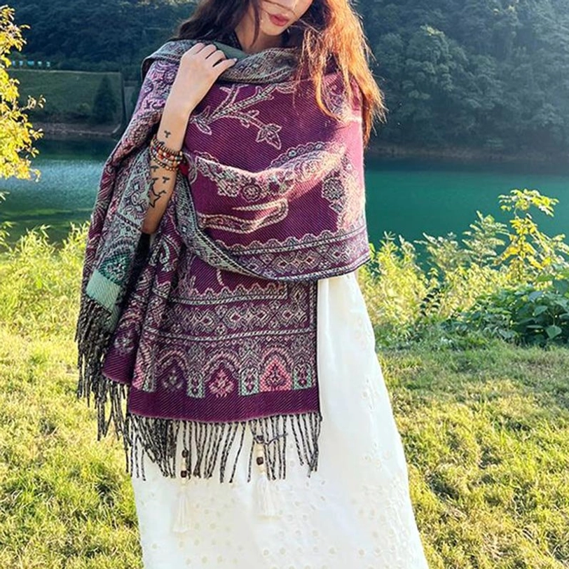 Purple-red Tibetan shawl with traditional leaf patterns, draped over shoulder with tassel bottom detail