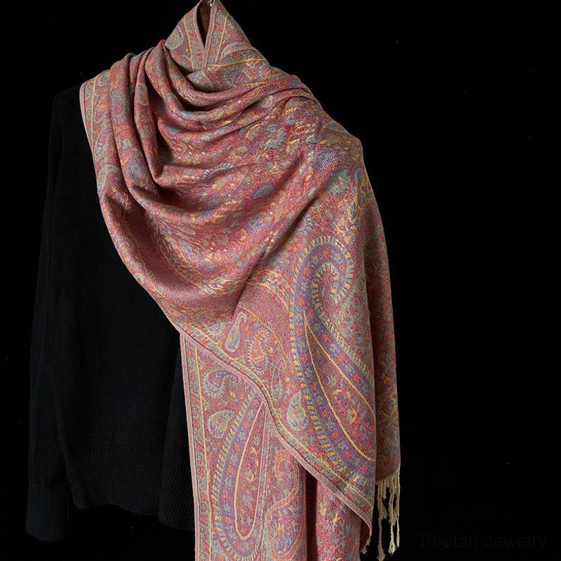 Tibetan light pink paisley tassel scarf draped on shoulders, showing cream-colored tassel hem detail