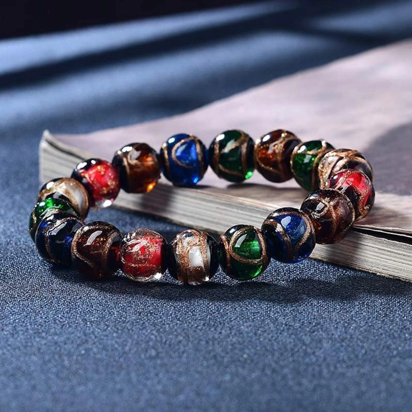 Tibetan incense ash liuli glass bead luck bracelet with multicolor five elements beads displayed on vintage book and dark blue fabric background