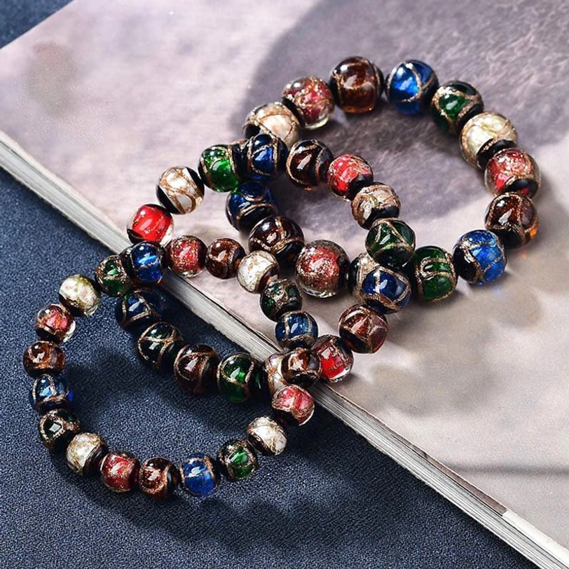 Two matching Tibetan incense ash glass bracelets with uniform multicolor beaded design placed on light vintage book