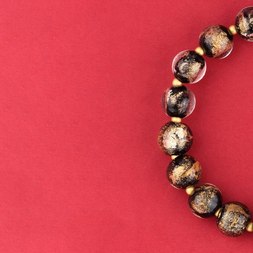 Tibetan spiritual bracelet with dark gold-sand spotted Liuli glass beads in side flat lay view