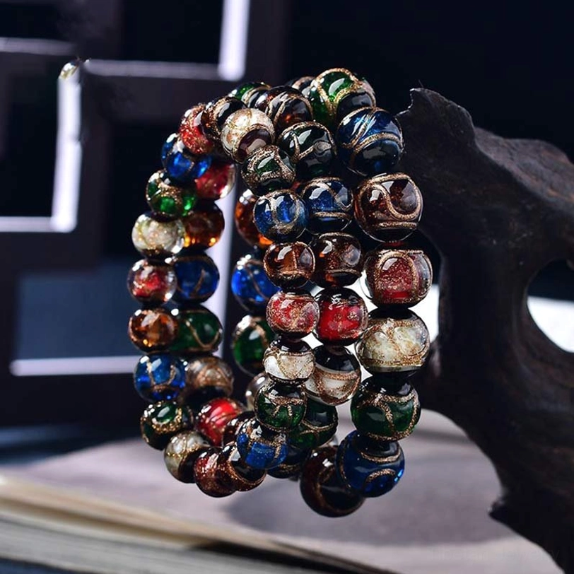 Stacked Tibetan colored glaze bracelets showing jewel-toned glass beads arranged on wooden decor and vintage book