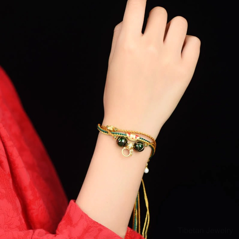 Tibetan five elements healing bracelet worn on wrist with red clothing backdrop showing fitted layered braided design in natural wear