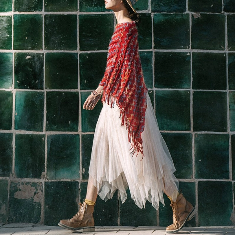 Long tassel tibetan travel knit shawl with draped fringes worn with tulle skirt and boots on outdoor ceramic tile area