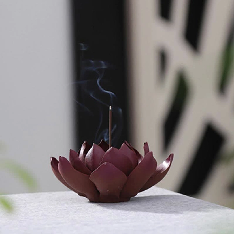 Purple clay lotus incense burner with smoking incense stick on minimalist indoor tabletop, three-quarter view