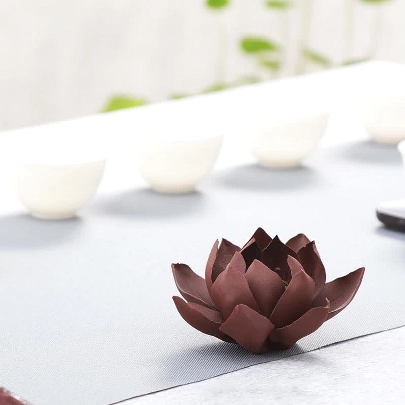 Compact dark brown handcrafted lotus incense burner high-angle side view on authentic tea table with bowls
