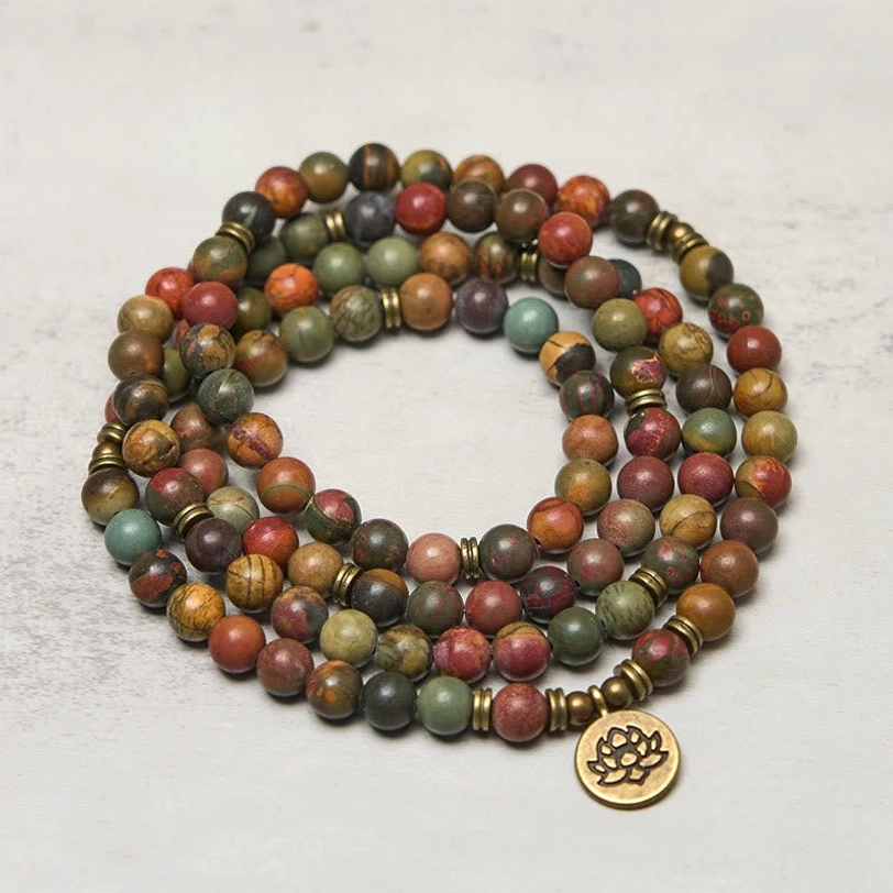 Lotus mala prayer beads side view displaying natural stone texture and brass charm detail on light background