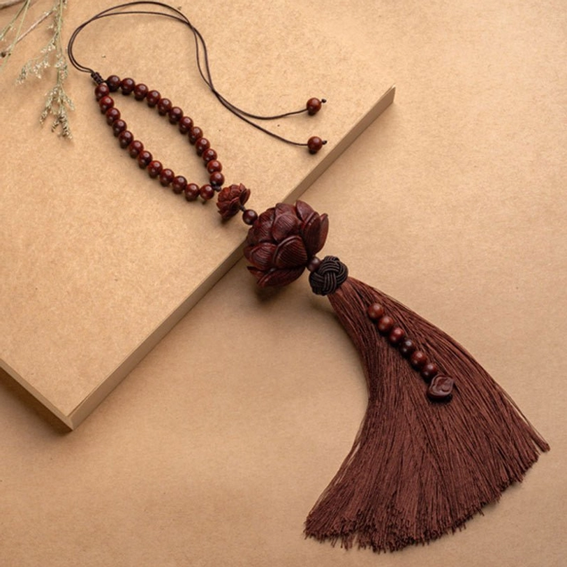 Wooden lotus charm tassel decoration flat lay on kraft paper background showing carved lotus top and beaded accent trim