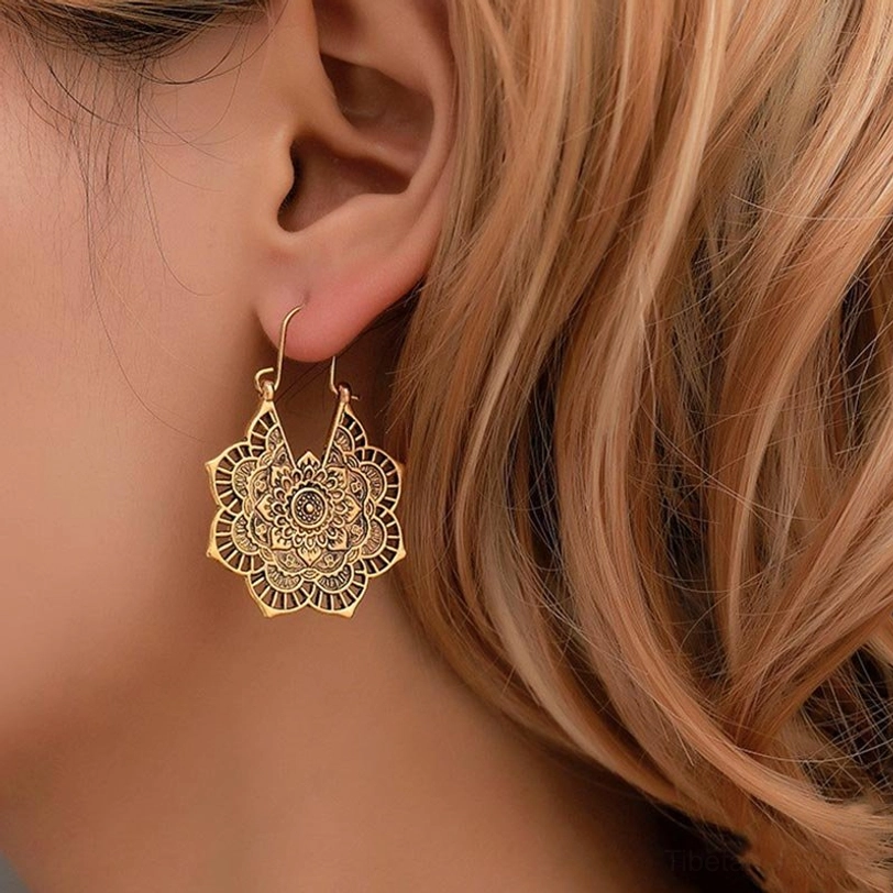 Tibetan lotus drop earrings on ear closeup worn showing fit and relief carving details
