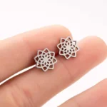 Tibetan lotus stud earrings silver finish held on fingertip showing intricate hollow cutout design