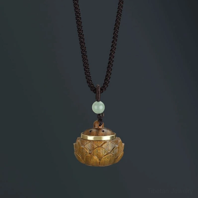 Tibetan lotus-shaped green sandalwood necklace pendant with light green spacer bead, vertical overhead shot on dark background