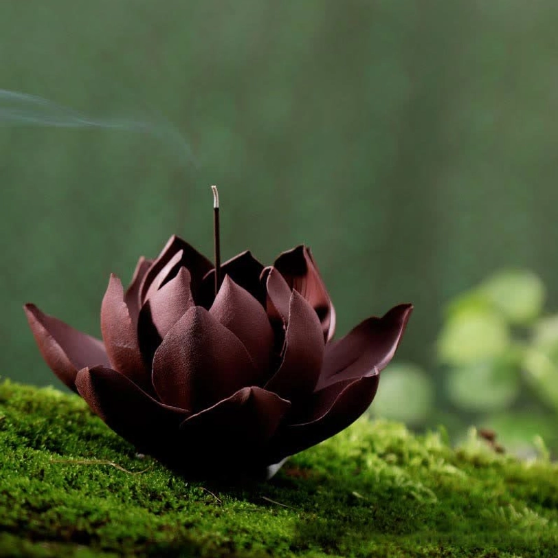 Handcrafted Tibetan lotus purple clay incense burner with deep maroon layered petals, side high-angle view on natural moss ground