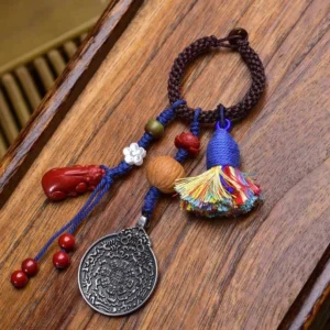 Lotus-style Tibetan protection keychain with brown braided rope, colorful tassel, silver Bagua plaque, and red gourd bead charm