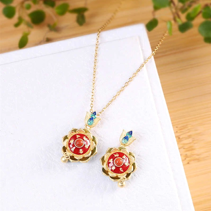 Pair of Tibetan lotus prayer wheel pendant necklaces in 925 sterling silver with red enamel centers and cloisonné lotus bails on white display board