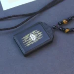 Ebony wood lotus pendant with inlaid sterling silver, front view showing carved lotus design and beaded cord necklace