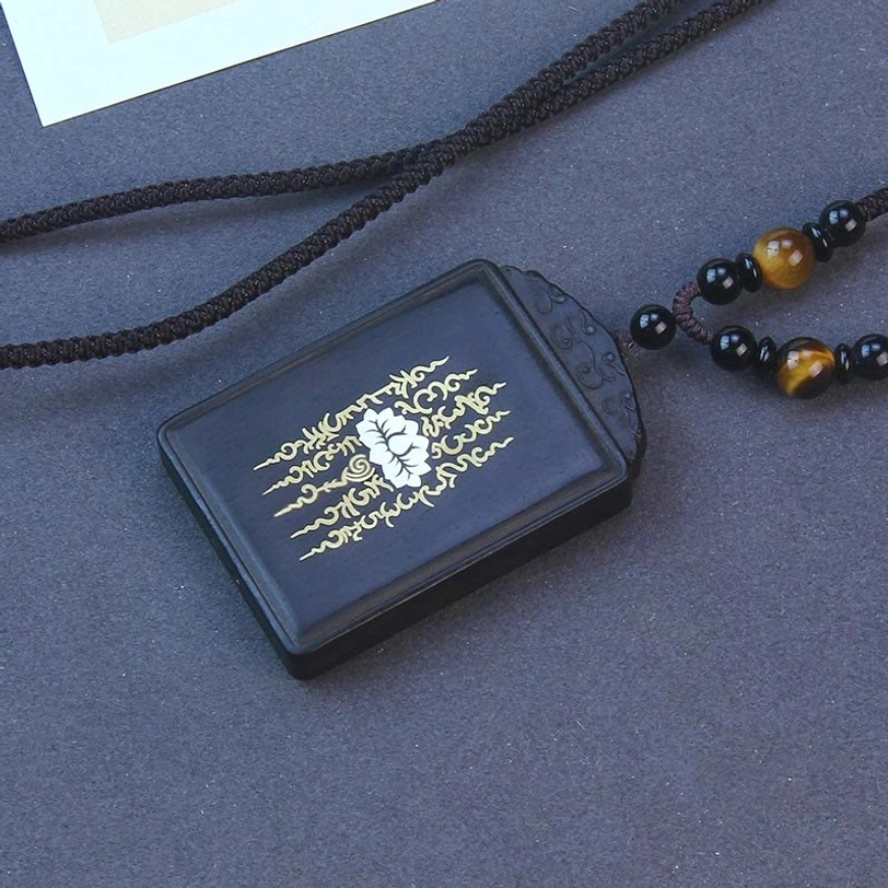 Ebony wood lotus pendant with inlaid sterling silver, front view showing carved lotus design and beaded cord necklace