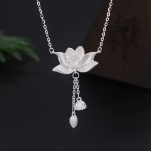 999 sterling silver lotus flower pod pendant with carved details and tassel charm, top-down studio view on dark background
