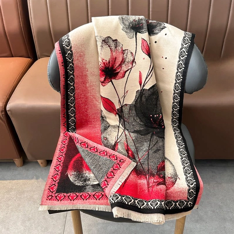 Dark red-black lotus print scarf draped on living room chair showing embroidered geometric border and soft woven texture