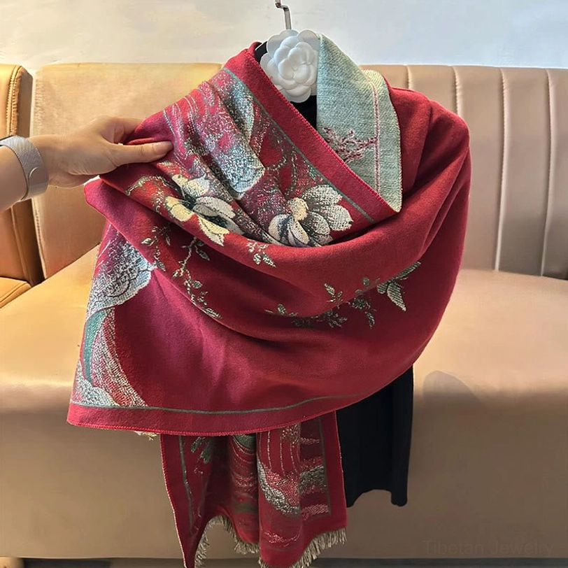 Hand-held draped view of red Tibetan shawl showing soft woven fabric and detailed motifs