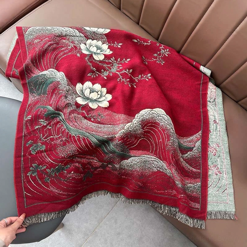 Deep red Tibetan shawl close-up with hand holding white floral wave print fringe