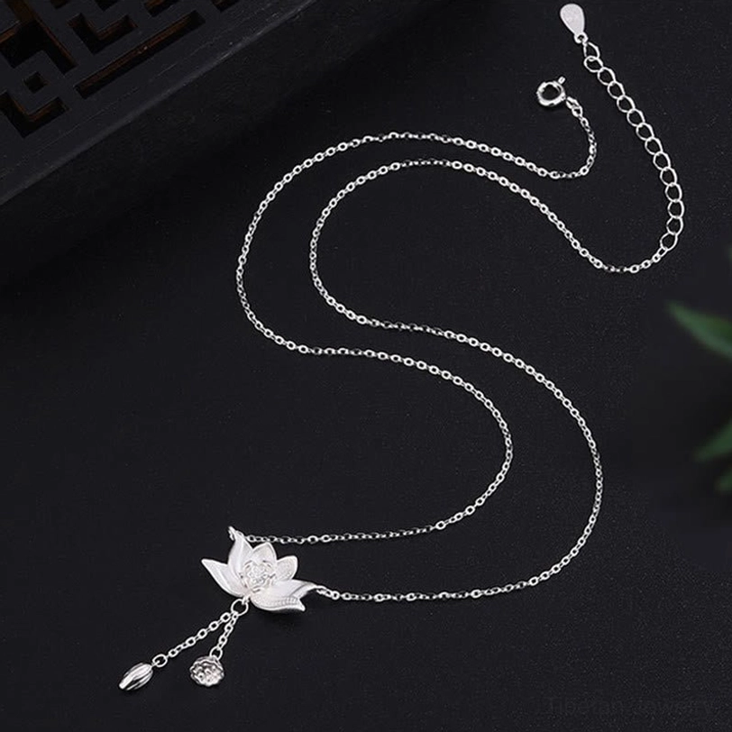 Adjustable sterling silver lotus necklace with extender chain and delicate tassel charm on dark studio background