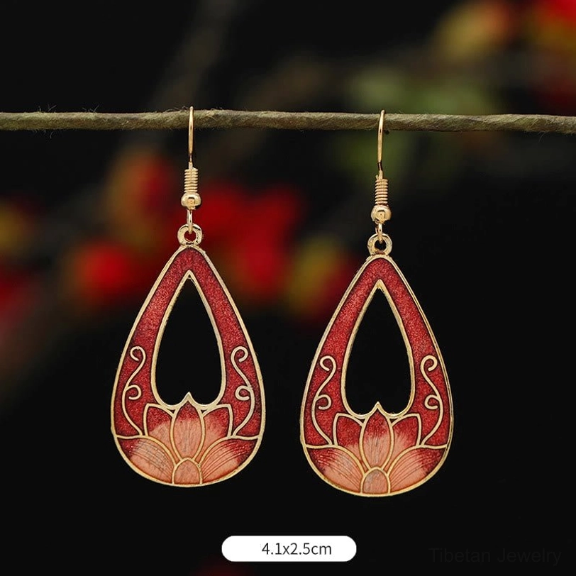 Red hollow teardrop lotus drop earrings 4.1x2.5cm with burgundy red and light pink enamel, hung on twig, blurred red floral backdrop