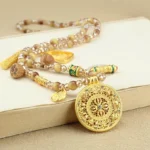 Tibetan lotus tiger eye beaded necklace with golden round pendant on light background