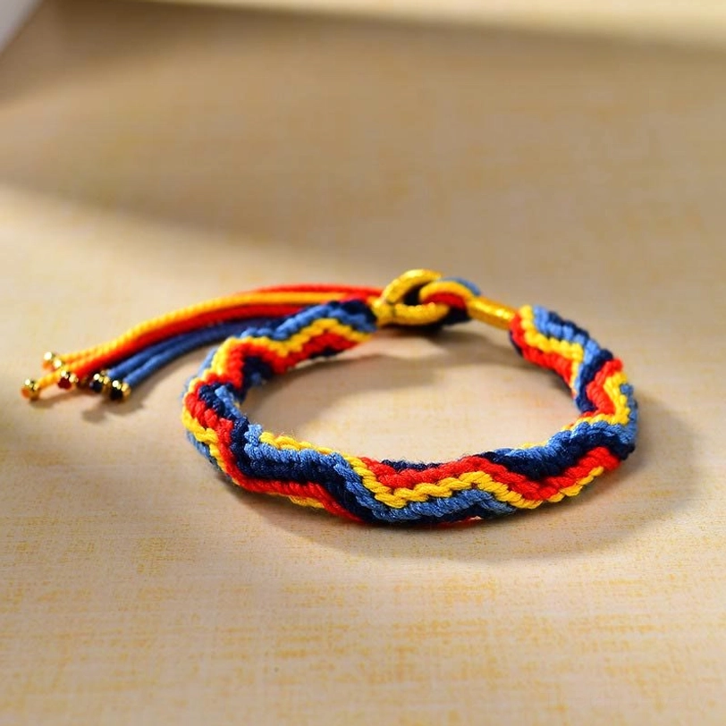 Tibetan style braided luck bracelet three-quarter view displaying colorful woven rope with gold tone fastener and decorative metal beads on tassels