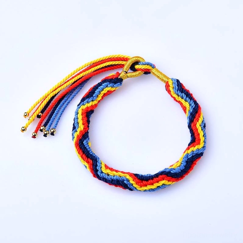 Chevron woven Tibetan luck bracelet in red blue yellow and gold color scheme with adjustable tassel closure on white background