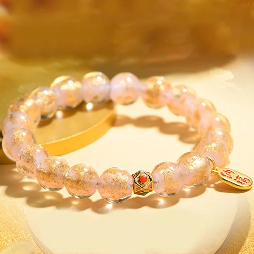 Incense ash glass bead lucky bracelet with zhao cai hanging charm and gold foil beads overhead view