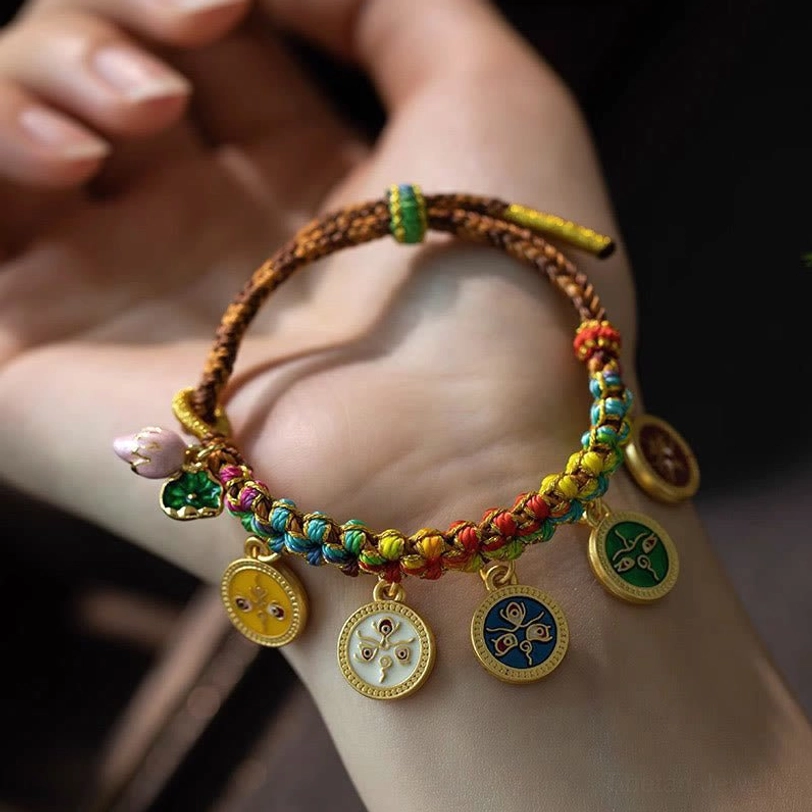 Tibetan prosperity bracelet displayed on palm showing brown woven rope with colorful braided sections and enamel charms