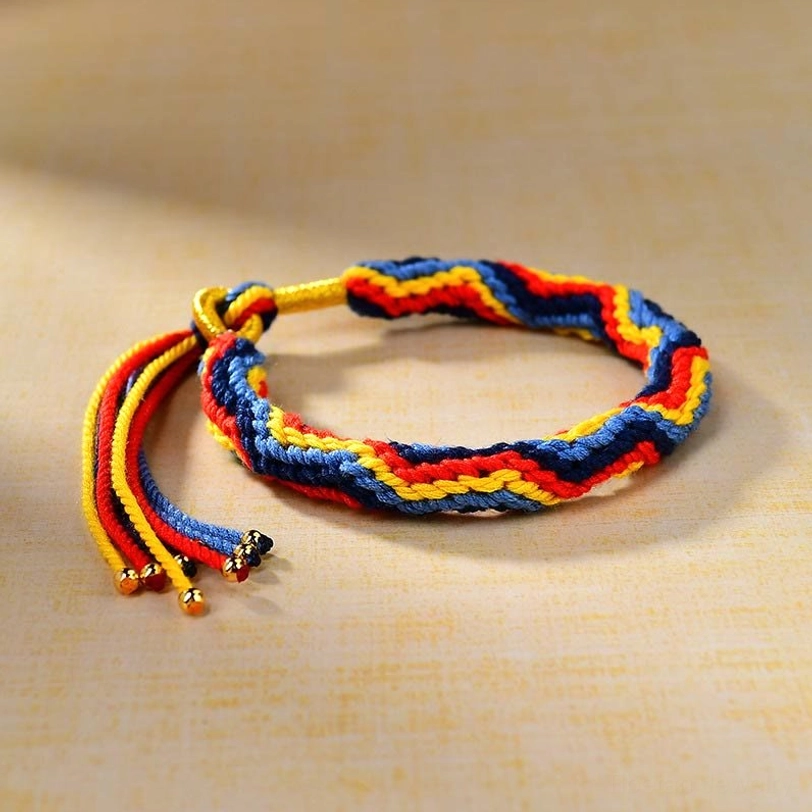 Multicolor woven Tibetan luck bracelet showing striped twisted weave pattern with adjustable tassel closure and gold bead charms