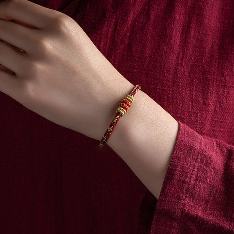 Red and gold braided Tibetan luck bracelet on wrist demonstrating comfortable fit