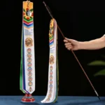 Tibetan Lucky Arrow prayer flag set with colorful silk ribbons, wooden pole and base on dark blue tabletop, front flat display view
