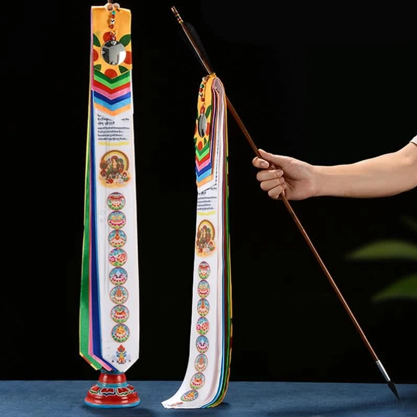 Tibetan Lucky Arrow prayer flag set with colorful silk ribbons, wooden pole and base on dark blue tabletop, front flat display view