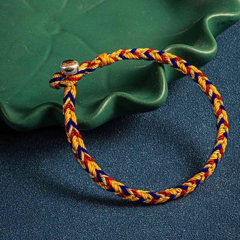 Tibetan multicolor lucky bracelet on decorative green tray with dark background showing craftsmanship