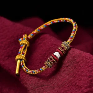 Handmade Dunhuang Tibetan lucky bracelet with multicolor braided cord and decorative knots on dark red background