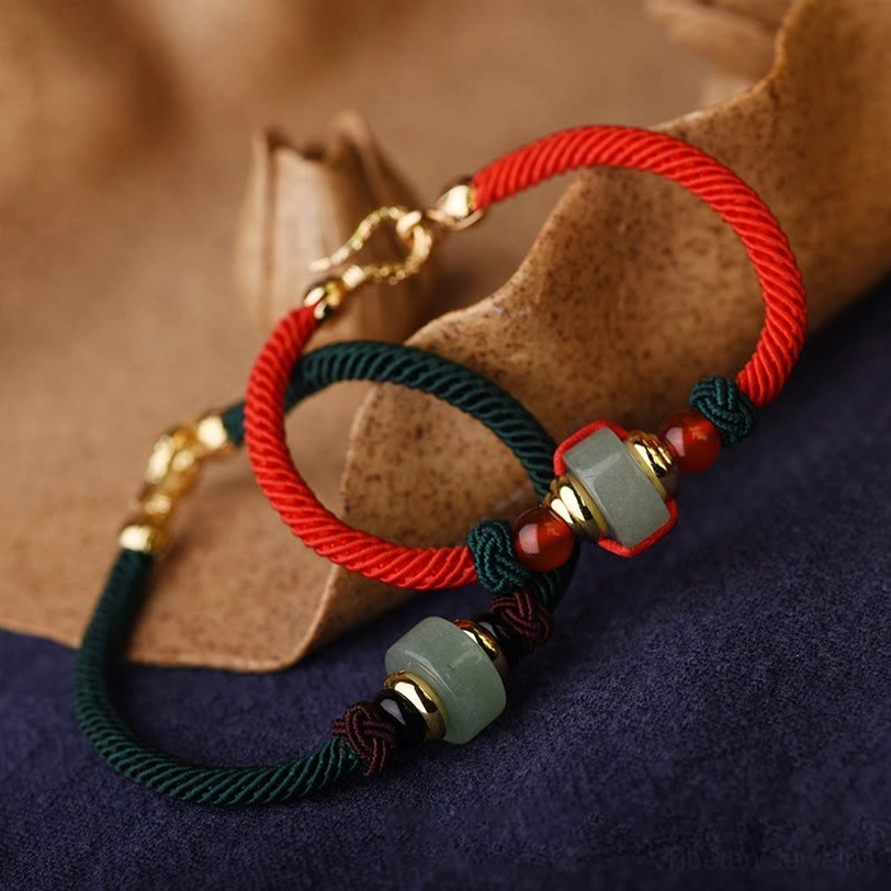 Handmade Tibetan lucky bracelet close-up showing woven red cord with jade and agate bead details and secure gold clasp