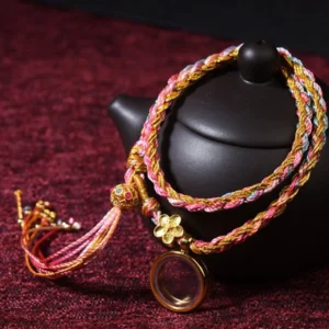 Tibetan handmade multicolor braided lucky bracelet with gold flower charm and tassel, double wrap design displayed on red velvet