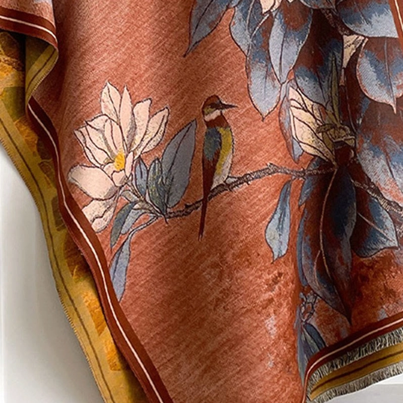 Close-up detail shot of Tibetan scarf showing handcrafted magnolia flower and bird print with stitched trim