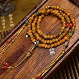 Tibetan 108 bone bead mala bracelet with dzi bead and copper accents on wooden surface - overhead view