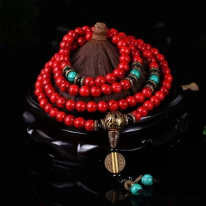 Tibetan red turquoise mala beads 108-bead strand overhead view with bronze hardware and turquoise accents on display stand