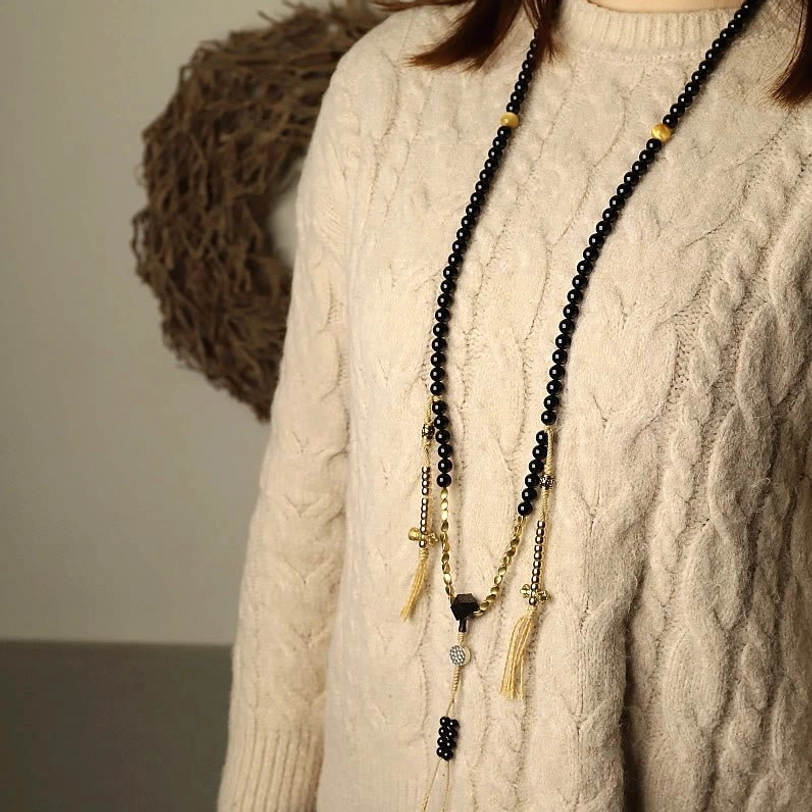 Tibetan mala bracelet worn on wrist showing black onyx beads and metal details in casual setting