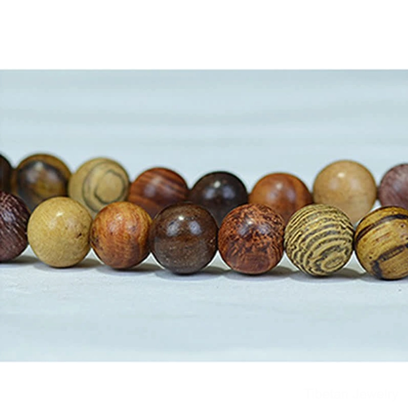 Close-up detail of diverse natural wood mala beads showing varied wood grain patterns and tones with white accent bead