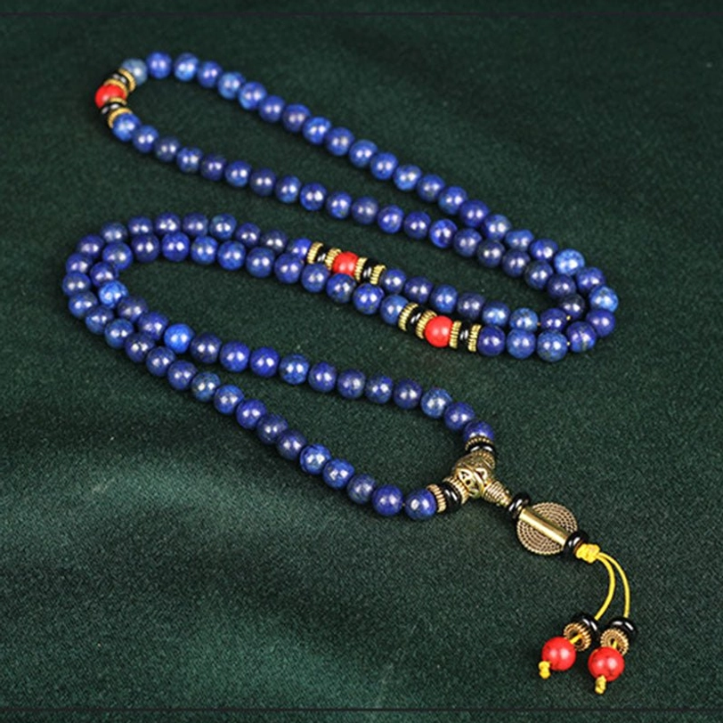 Long lapis lazuli prayer beads mala flat lay showing full strand with bronze metal hardware and red tassel charm
