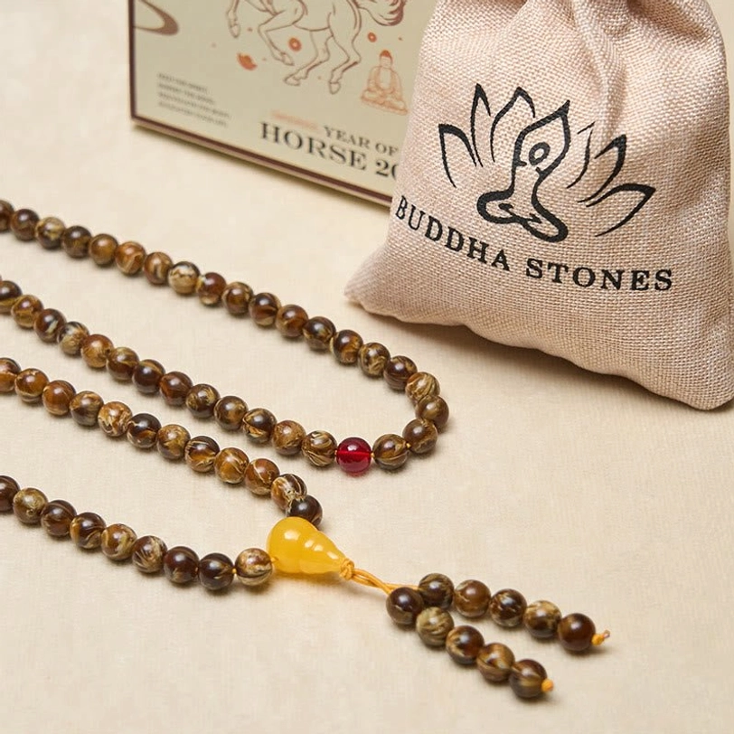 Tibetan amber mala with gourd charm displayed alongside branded linen pouch and gift box packaging