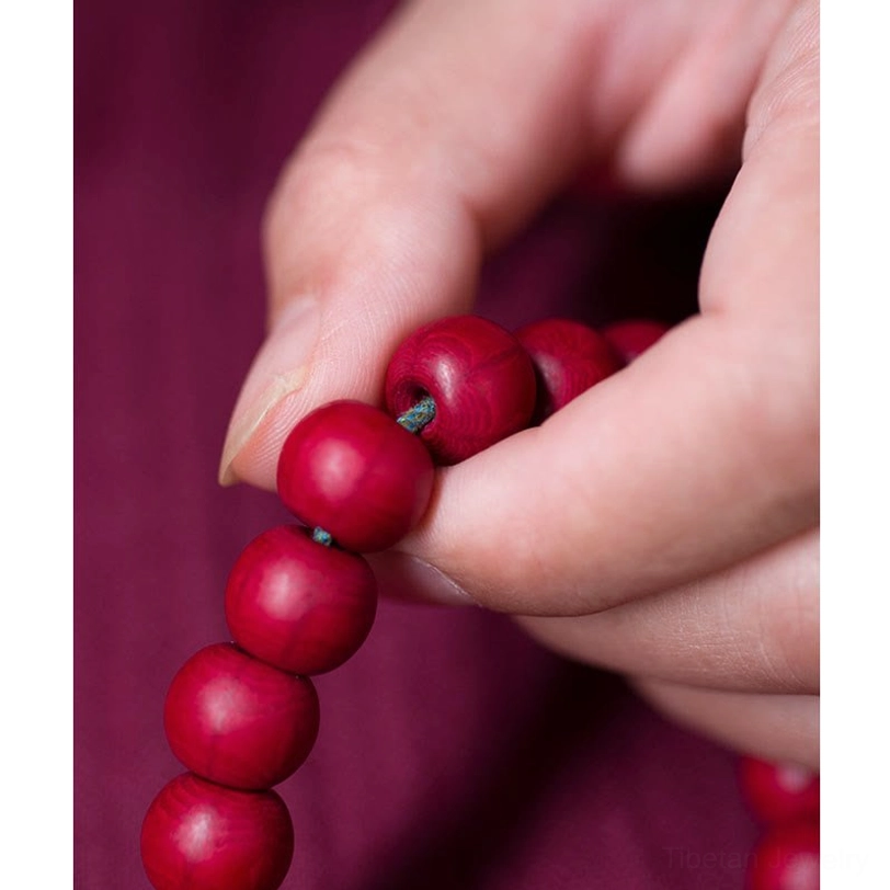Hand-held red wooden mala beads close-up finger level view natural material