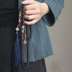 Hand-held Tibetan 108-bead mala prayer beads with dzi bead and blue tassel worn as necklace close-up detail