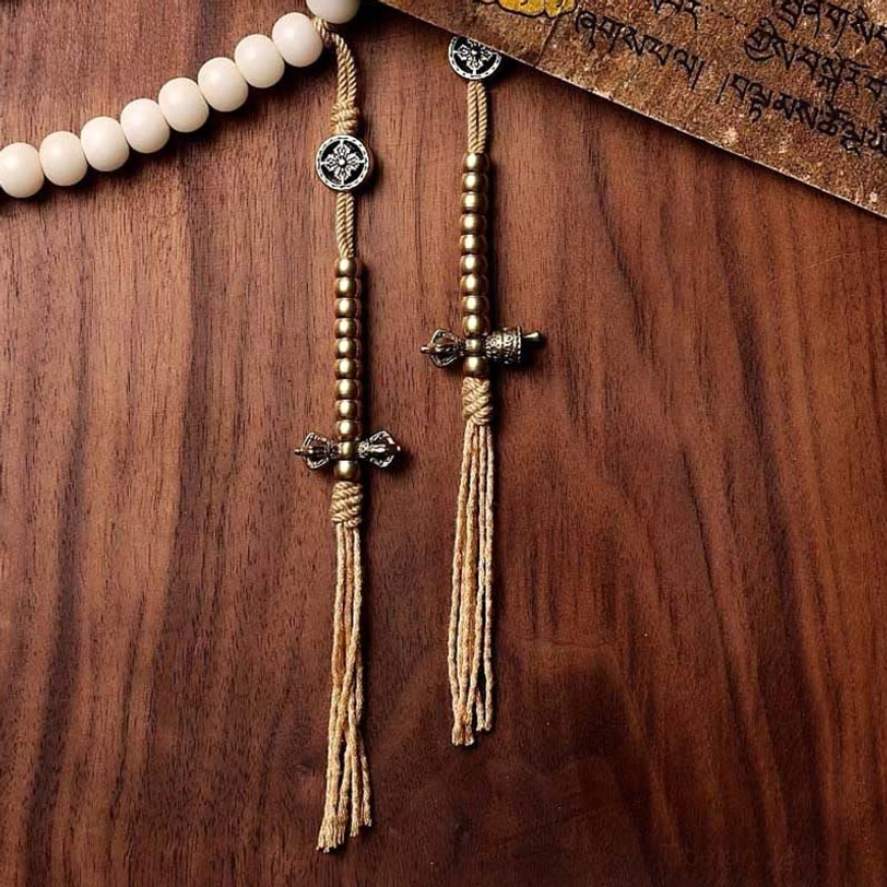 Tibetan mala prayer beads with silver vajra tassel pendant and white bodhi seeds on vintage Buddhist scripture background